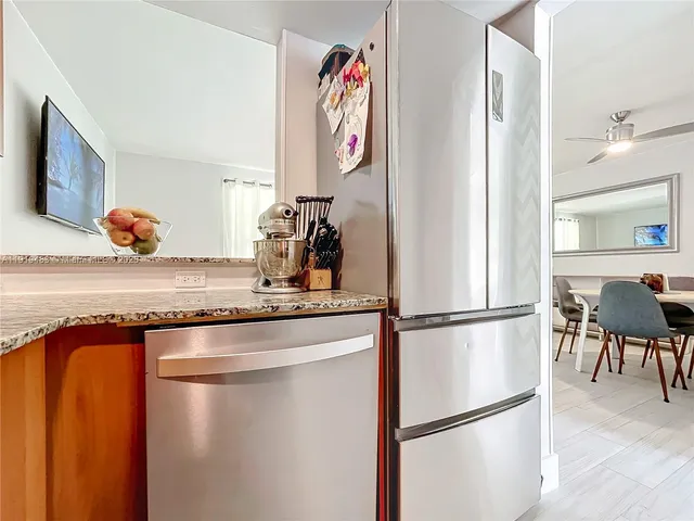 a kitchen with stainless steel appliances granite countertop a refrigerator a microwave a stove and a refrigerator with wooden floor