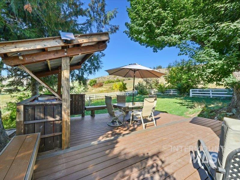 2651 Fruitvale Glendale Road Council, ID 83612 - Photo 18 of 24 Expansive outdoor deck featuring wood-finish composite decking, a built-in wood-paneled structure with a sloped roof, and a mature tree providing natural shade