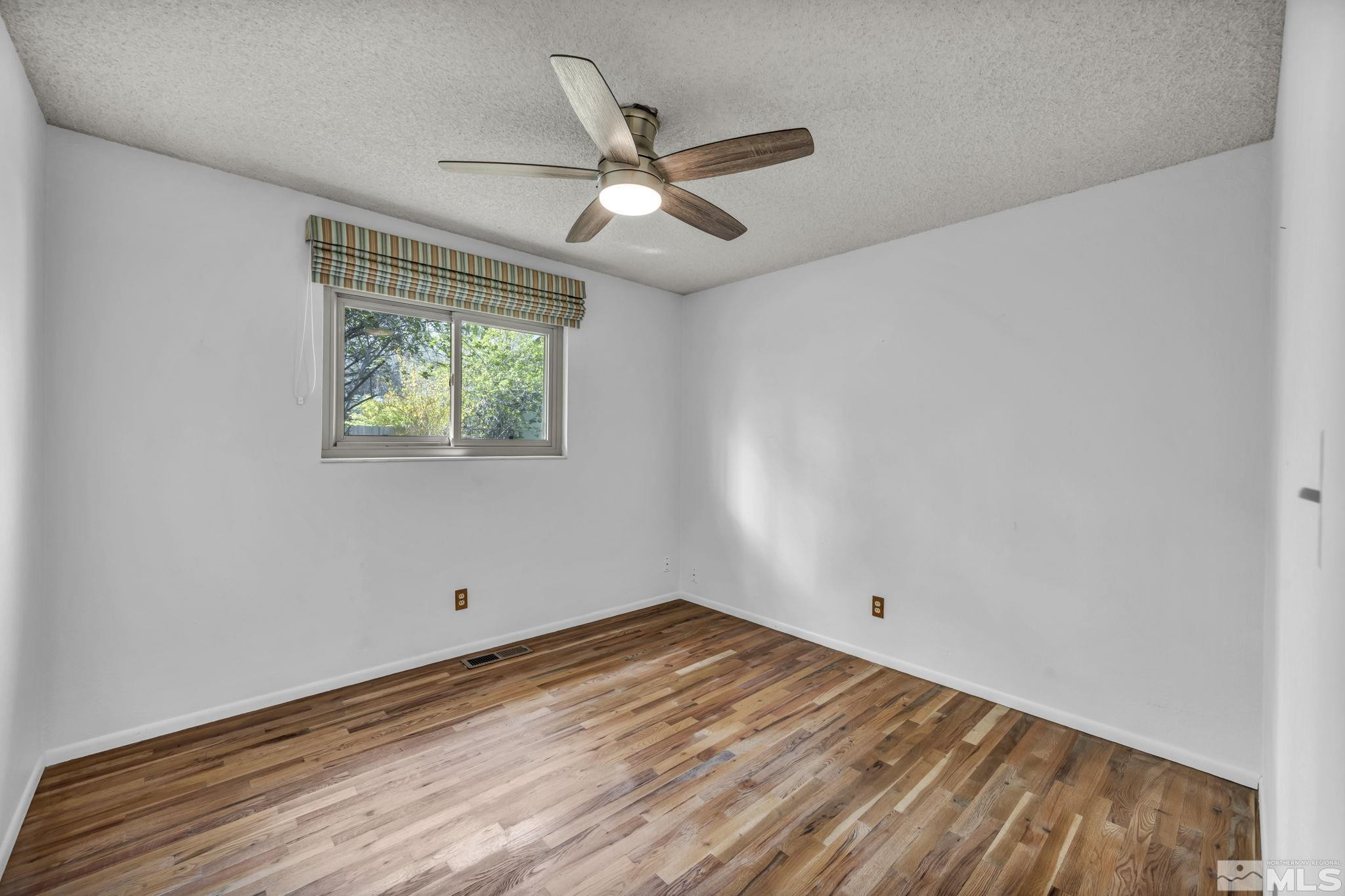 909 Norrie Drive Carson City, NV 89703 - Photo 24 of 39 an empty room with wooden floor ceiling fan and windows