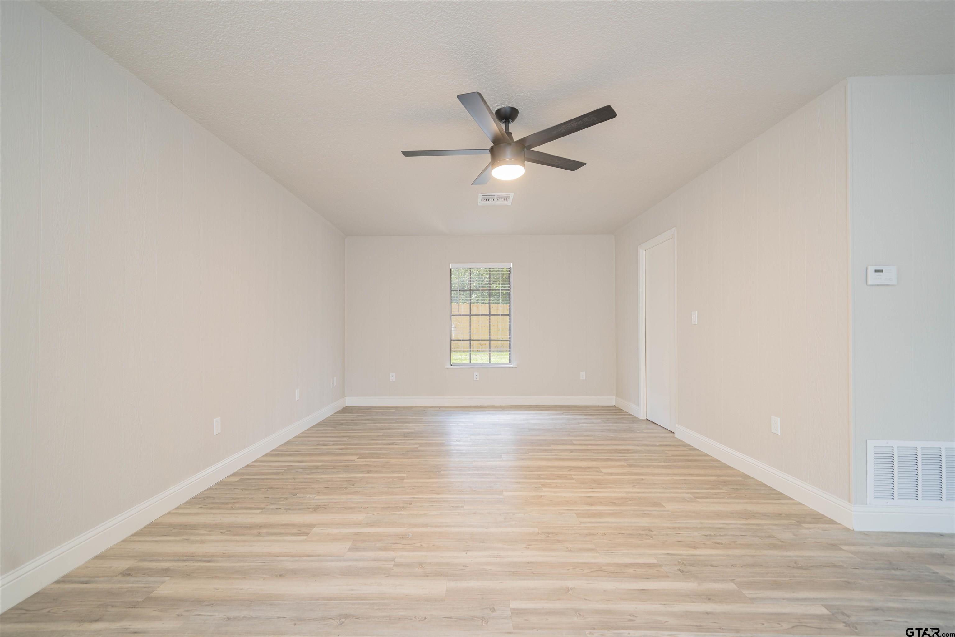 291 Taylor George Road Longview, TX 75605 - Photo 11 of 35 a view of an empty room with wooden floor and a window