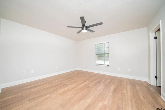 a view of empty room with wooden floor and fan