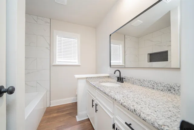 a bathroom with a granite countertop sink a mirror and shower