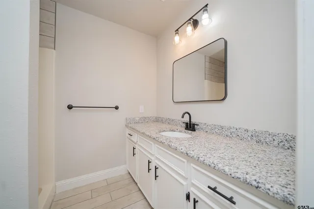 a bathroom with a granite countertop sink and mirror