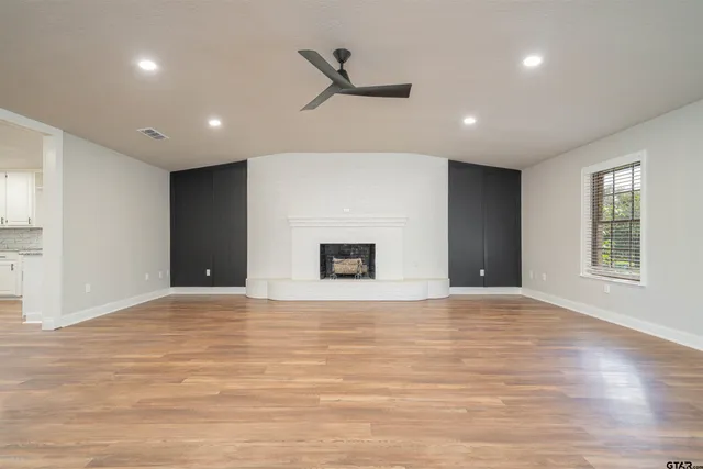 a view of an empty room with window and a ceiling fan
