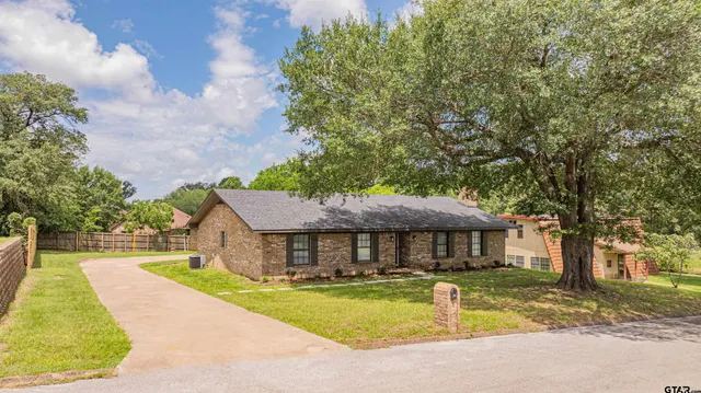 a front view of house with yard and trees in the background