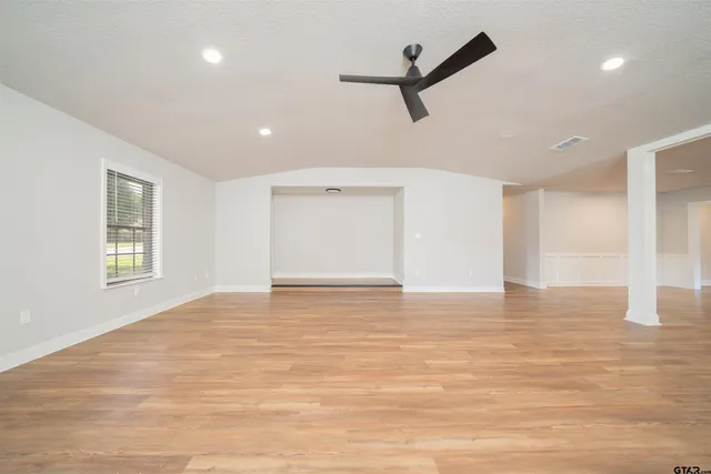 a view of an empty room with window and a ceiling fan