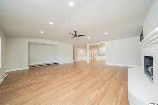 a view of empty room with wooden floor and fireplace