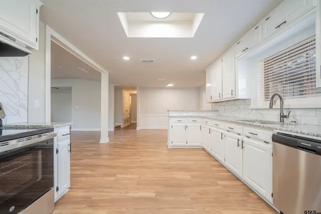 a large kitchen with granite countertop a stove top oven a sink a counter space and cabinets