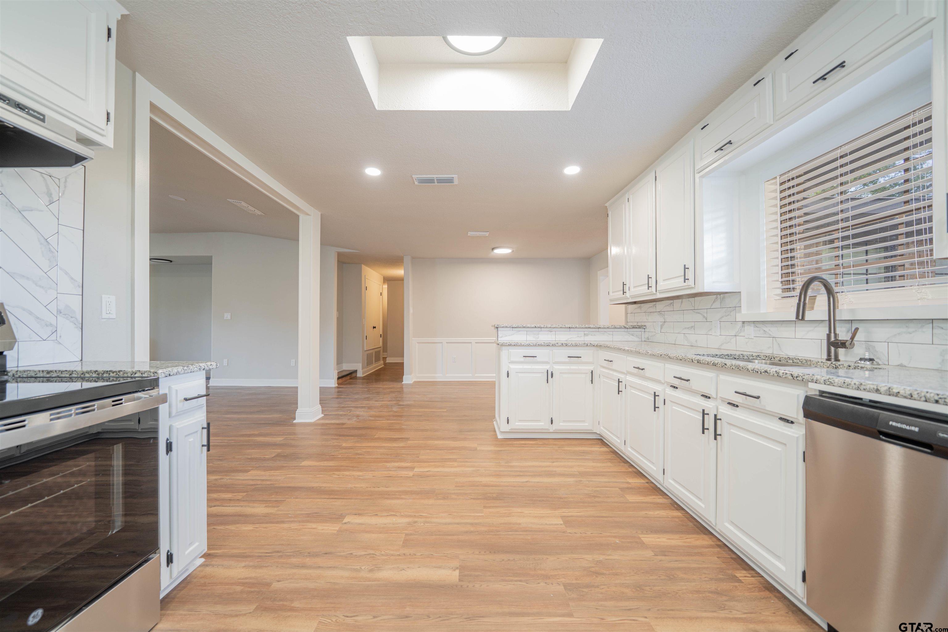 291 Taylor George Road Longview, TX 75605 - Photo 10 of 35 a large kitchen with granite countertop a stove top oven a sink a counter space and cabinets