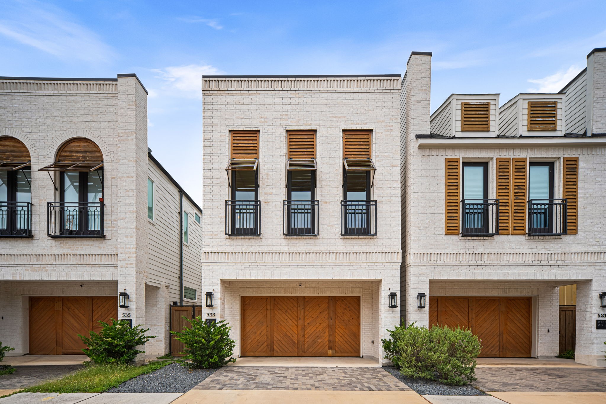 Modern, recent construction (2021) with a clean, contemporary façade featuring light brickwork and wooden accents. A private double-wide driveway, a two-car garage and large windows with shutters offer a stylish and inviting exterior.
