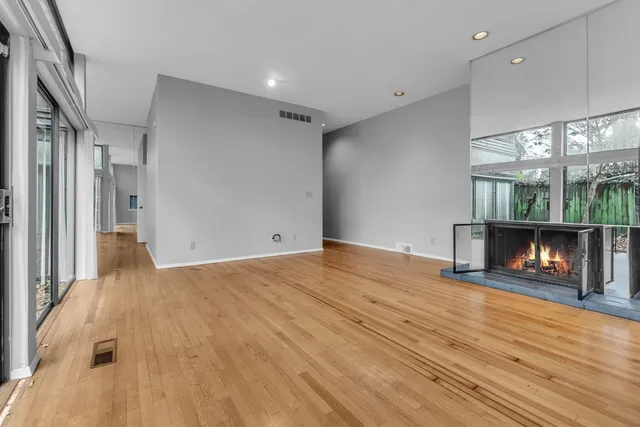 a view of an empty room with wooden floor a fireplace