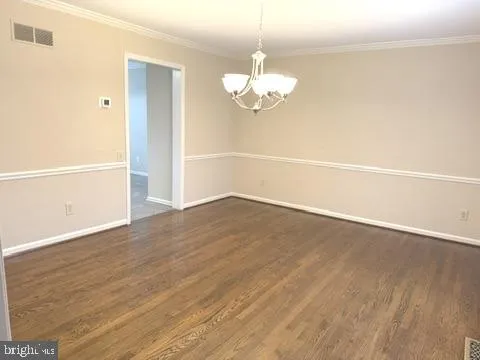 an empty room with wooden floor and chandelier