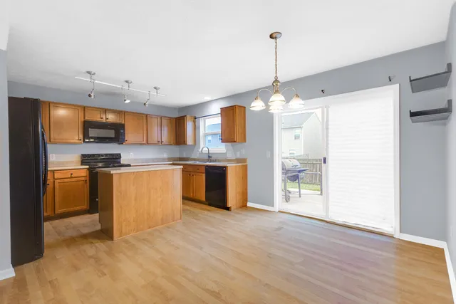 a kitchen with stainless steel appliances granite countertop a refrigerator a sink dishwasher a stove with white cabinets and wooden floor