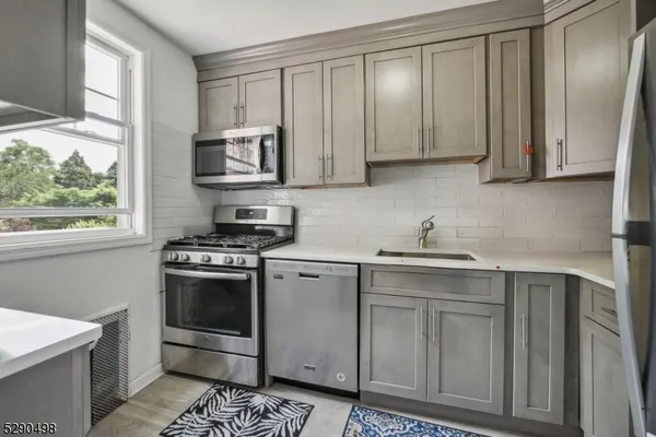 a kitchen with stainless steel appliances granite countertop a stove a sink and a microwave