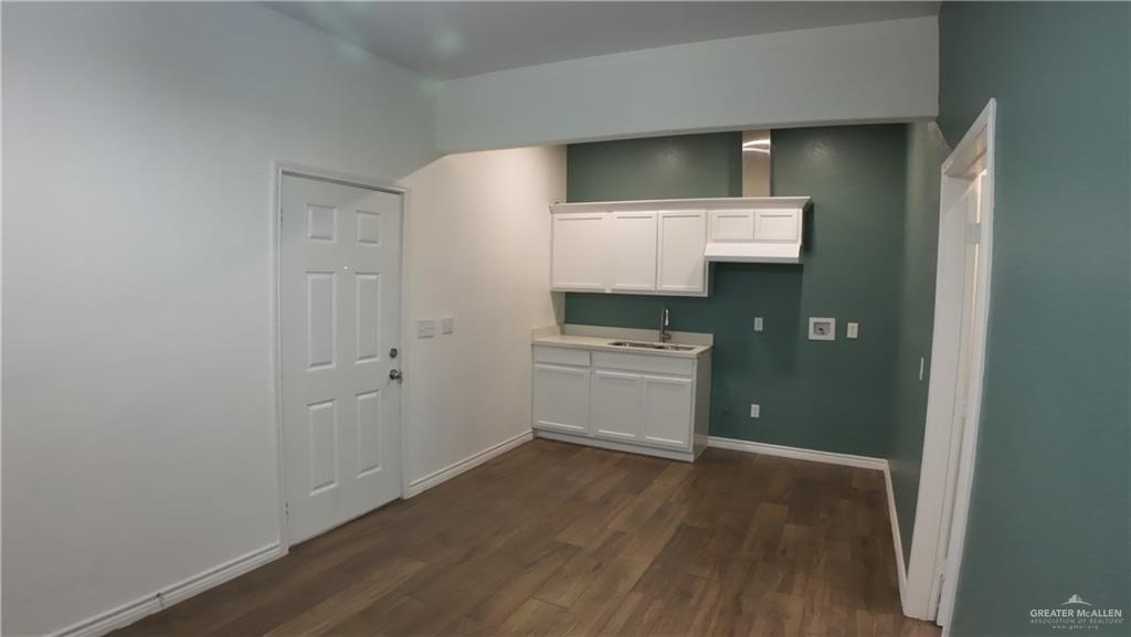 1421 South Dallas Street Alton, TX 78573 - Photo 1 of 7 a kitchen with a wooden floor and white cabinets