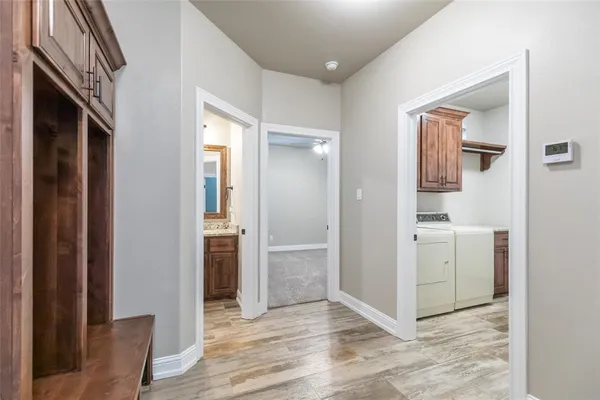 a view of a hallway with wooden floor and a bathroom