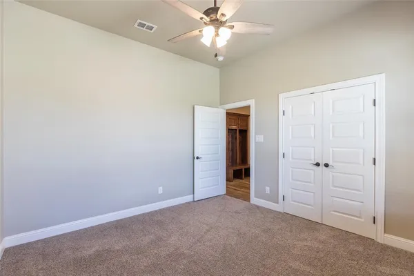 an empty room with closet and a ceiling fan
