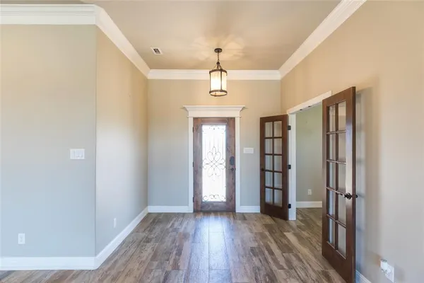 a hallway with wooden floor chandelier and entryway