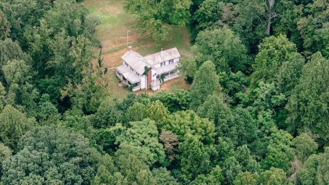 an aerial view of residential house with outdoor space and trees all around