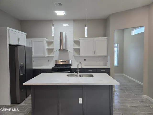 a kitchen with a sink a refrigerator and white cabinets