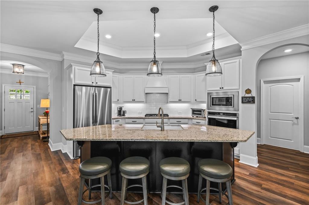 4883 Pleasantry Way Northwest Acworth, GA 30101 - Photo 11 of 46 a kitchen with kitchen island granite countertop a table chairs sink and wooden floor