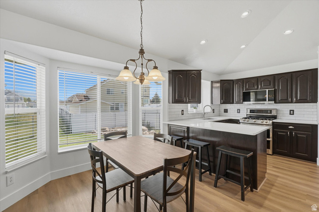 5576 South 4100th Street West Roy, UT 84067 - Photo 11 of 35 Open-concept kitchen and dining area featuring dark wood cabinetry, white subway tile backsplash, and light countertops