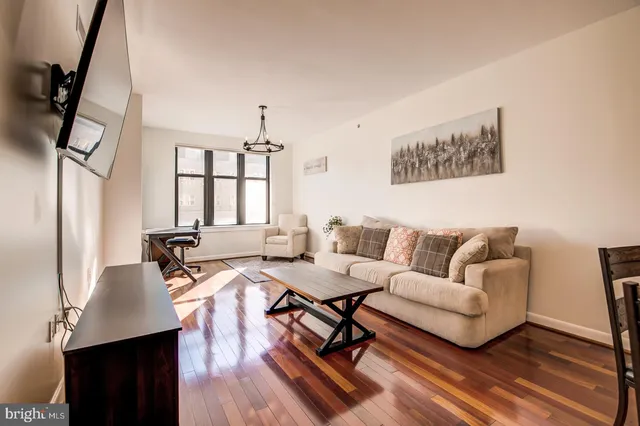 a living room with furniture a large window and wooden floor