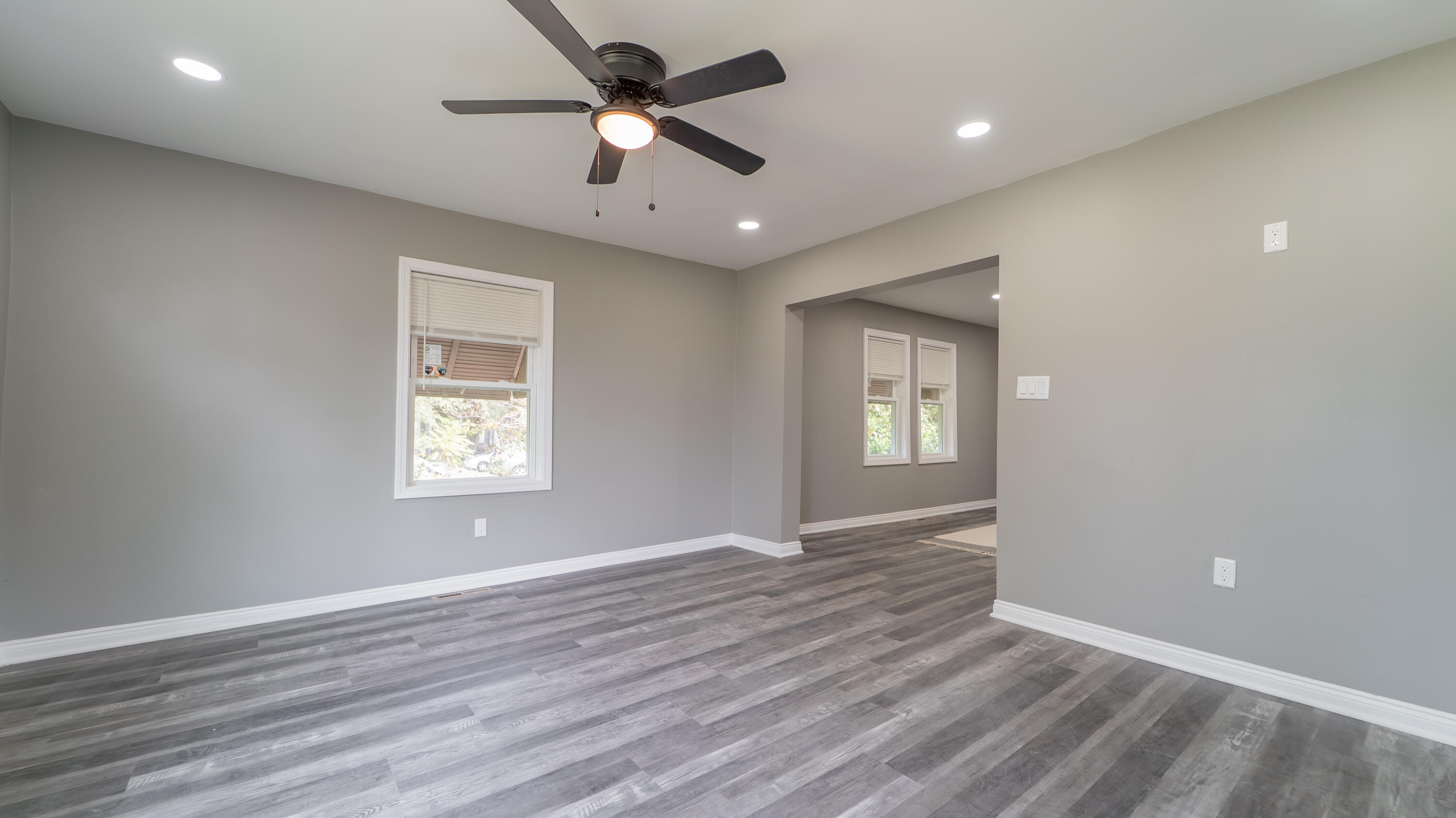 2257 West 16th Avenue Gary, IN 46404 - Photo 3 of 24 an empty room with wooden floor ceiling fan and windows