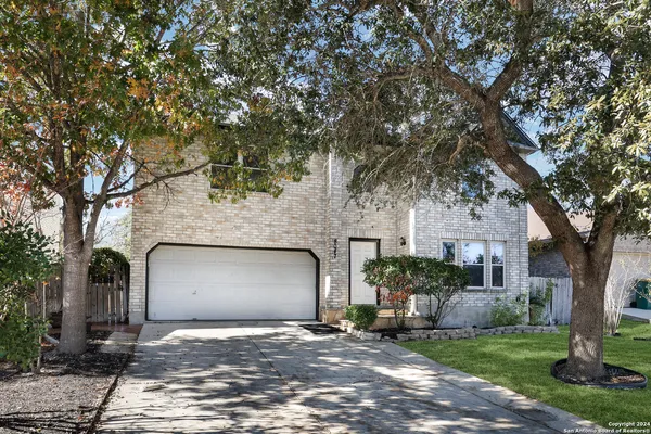 a front view of a house with a garden and tree