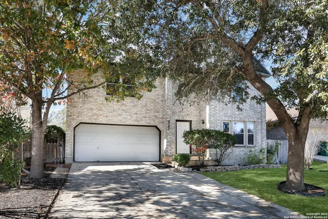 a front view of a house with a garden and tree