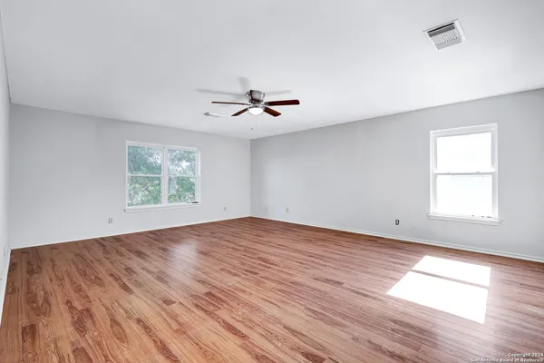 an empty room with wooden floor and windows