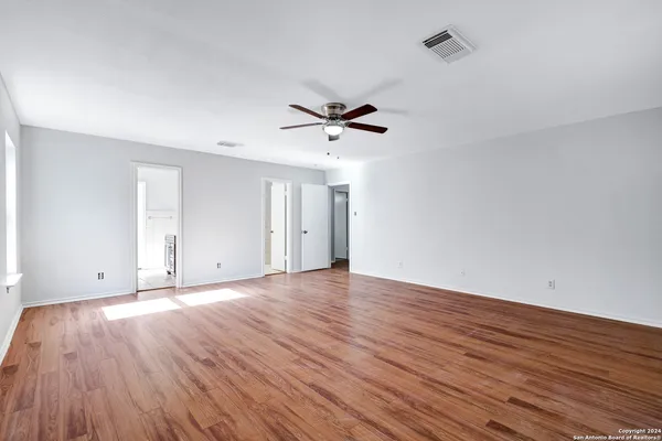a view of a room with wooden floor and a ceiling fan