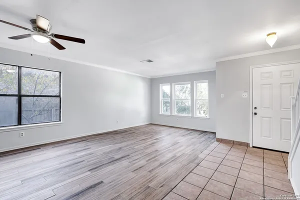 a view of an empty room with a window and wooden floor