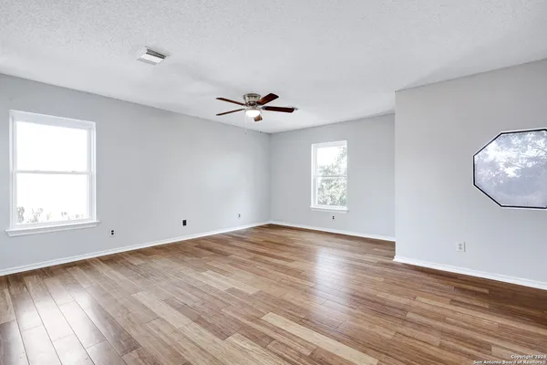 an empty room with wooden floor and windows