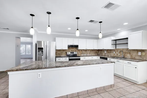 a kitchen with stainless steel appliances granite countertop a sink a stove a refrigerator and island with wooden floor