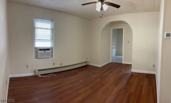 an empty room with wooden floor chandelier fan and windows