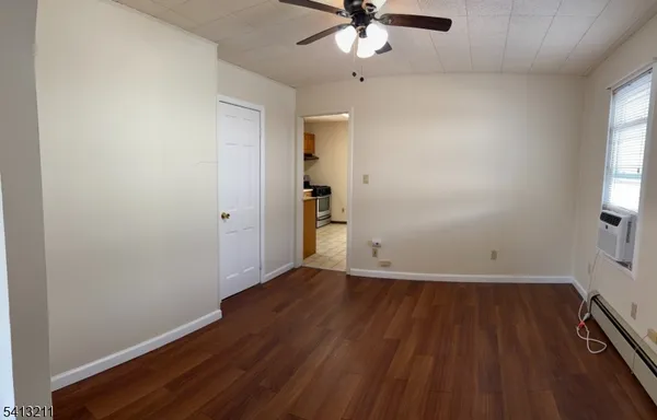 an empty room with wooden floor fan and windows