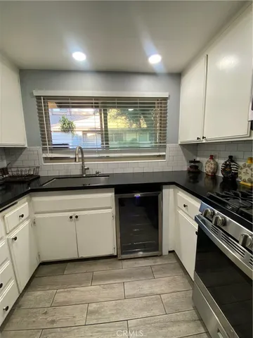 a kitchen with granite countertop white cabinets sink and appliances