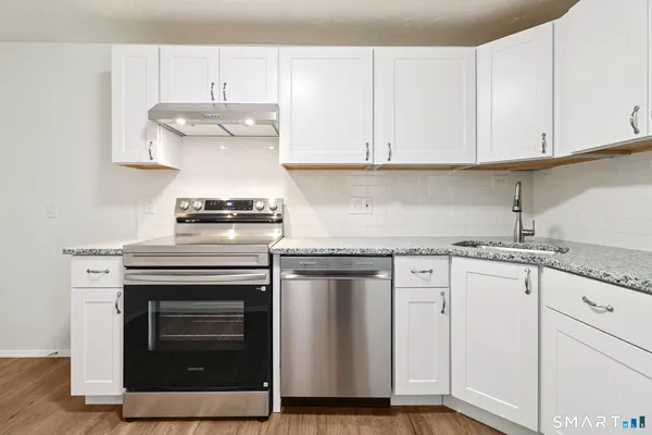 a kitchen with granite countertop white cabinets and white appliances