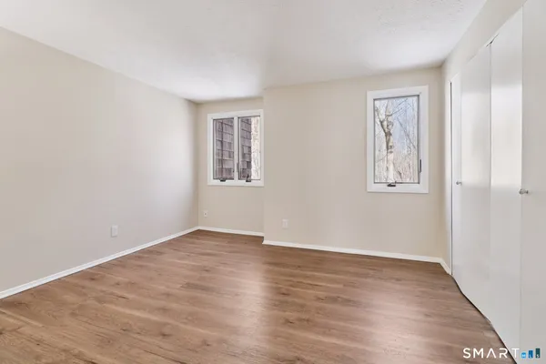 an empty room with wooden floor and windows