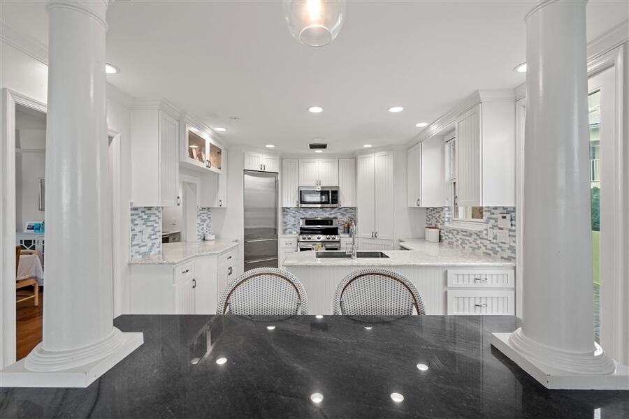 5111 North Ocean Boulevard, Unit A Ocean Ridge, FL 33435 - Photo 22 of 47 a kitchen with kitchen island granite countertop a stove a sink a refrigerator and white cabinets with wooden floor