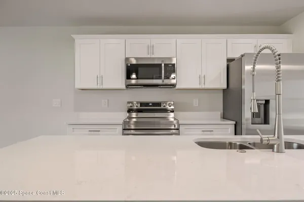 a kitchen with stainless steel appliances granite countertop a sink a stove and a refrigerator