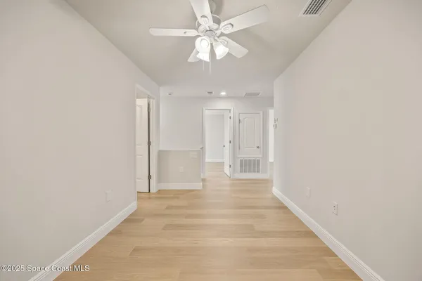 an empty room with wooden floor and ceiling fan