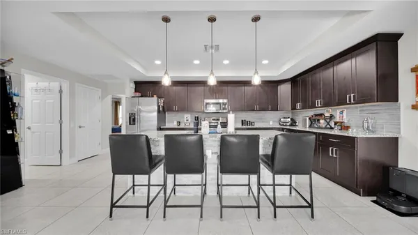 a kitchen with stainless steel appliances kitchen island granite countertop a sink a stove a dining table and chairs