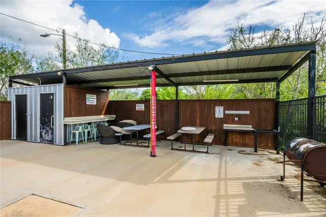 a view of a patio with a table and chairs under an umbrella with a small yard