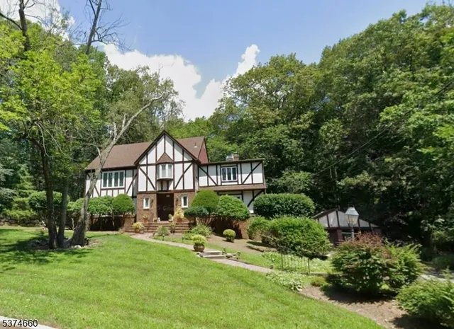 a view of a house with a big yard plants and large trees