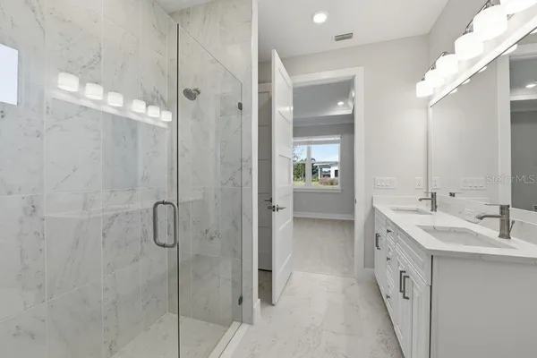 a spacious bathroom with a double vanity sink a mirror and a shower