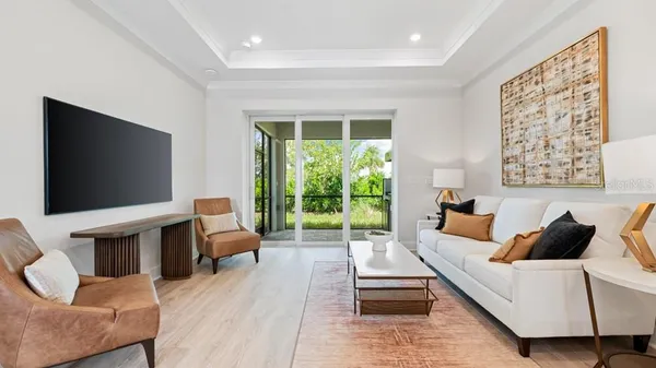 a living room with furniture a flat screen tv and a floor to ceiling window