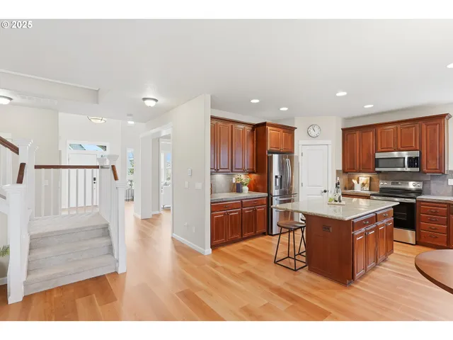 a kitchen with stainless steel appliances granite countertop a refrigerator oven a sink dishwasher and white cabinets with wooden floor