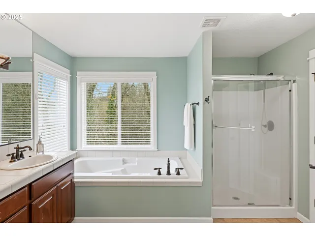 a bathroom with a bathtub sink double vanity and mirror